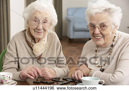 Stock Photograph - Two Senior Women Playing Dominoes At Day Care Centre. Fotosearch