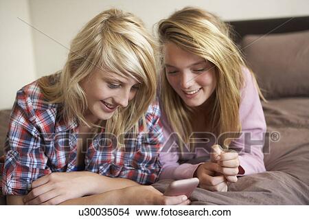 Picture - Two Teenage Girls Lying On Bed Looking At Pregnancy Testing Kit. Fotosearch