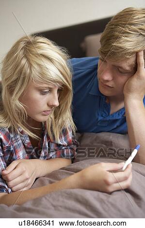 Stock Image - Two Teenage Girls Lying On Bed Looking At Pregnancy Testing Kit. Fotosearch