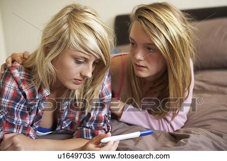 Stock Photography - Two Teenage Girls Lying On Bed Looking At Pregnancy Testing Kit. Fotosearch