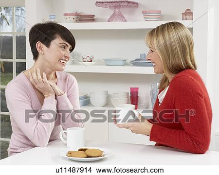 Two Women Enjoying Hot Drink In Kitchen View Large Photo Image Picture - Two Women Enjoying Hot Drink In Kitchen. Fotosearch