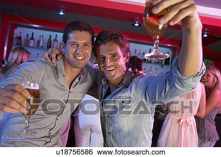Stock Photograph - Two Young Men Having Fun In Busy Bar. Fotosearch