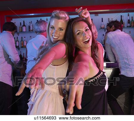 Stock Image - Two Young Women Having Fun In Busy Bar. Fotosearch