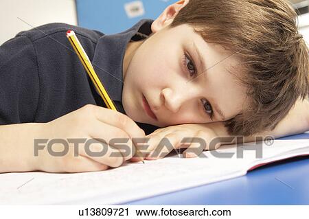 Stock Image - Unhappy Schoolboy Studying In Classroom. Fotosearch