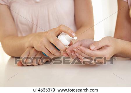 Stock Photo - Woman hand applying hand sanitizer. Fotosearch