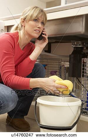 Woman Mopping Up Leaking Sink On Phone To Plumber View Large Photo Image Stock Photo - Woman Mopping Up Leaking Sink On Phone To Plumber. Fotosearch