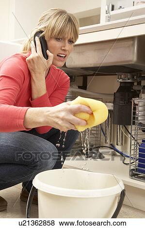 Woman Mopping Up Leaking Sink On Phone To Plumber View Large Photo Image Stock Photo - Woman Mopping Up Leaking Sink On Phone To Plumber. Fotosearch