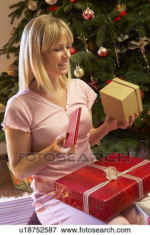 Woman Opening Christmas Present In Front Of Tree View Large Photo Image Stock Photo - Woman Opening Christmas Present In Front Of Tree. Fotosearch