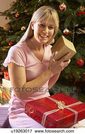Woman Opening Christmas Present In Front Of Tree View Large Photo Image Stock Photo - Woman Opening Christmas Present In Front Of Tree. Fotosearch