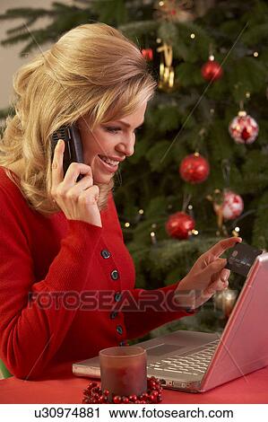 Stock Image - Woman Shopping Online For Christmas Gifts On Phone. Fotosearch