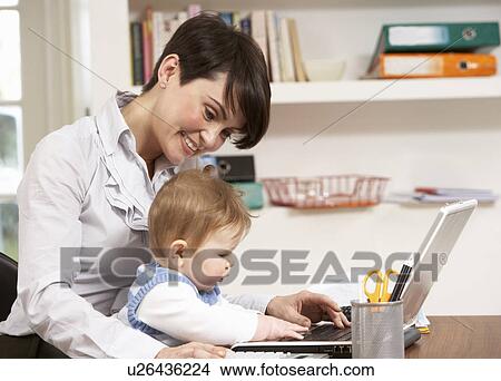 Picture - Woman With Baby Working From Home Using Laptop. Fotosearch