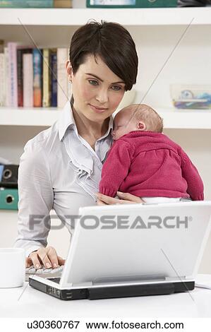 Stock Photo - Woman With Newborn Baby Working From Home Using Laptop. Fotosearch