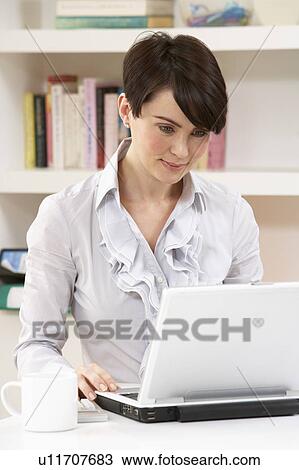Stock Image - Woman Working From Home Using Laptop. Fotosearch