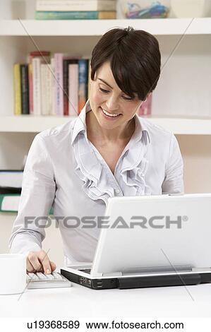 Stock Photo - Woman Working From Home Using Laptop. Fotosearch
