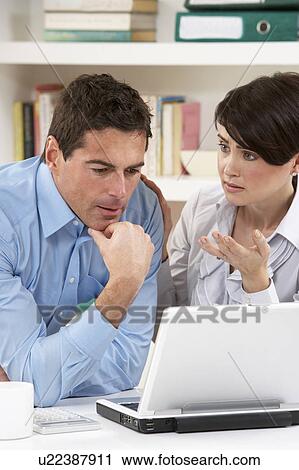 Stock Image - Worried Couple Working From Home Using Laptop. Fotosearch