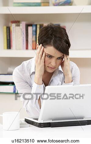 Stock Image - Worried Looking Woman Working From Home Using Laptop. Fotosearch