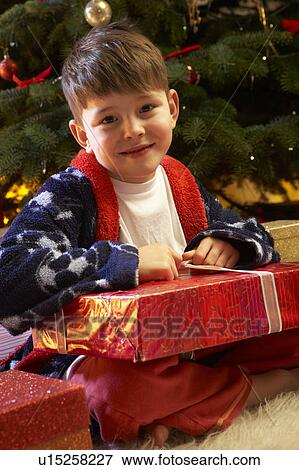 Young Boy Opening Christmas Present In Front Of Tree View Large Photo Image Stock Photo - Young Boy Opening Christmas Present In Front Of Tree. Fotosearch