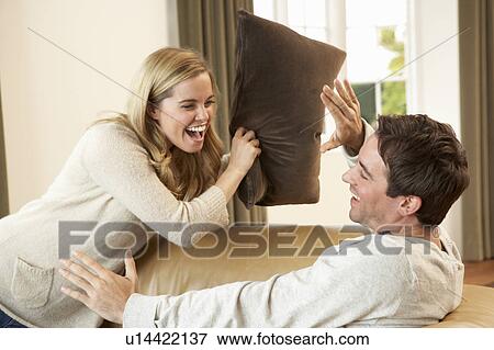 Stock Photo - Young couple having fun laughing on sofa. Fotosearch
