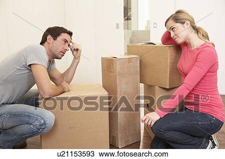Stock Image - Young couple looking upset among boxes. Fotosearch