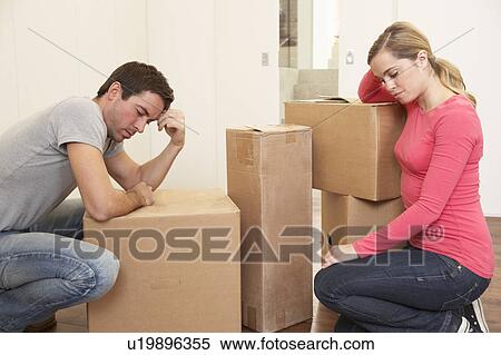 Stock Photography - Young couple looking upset among boxes. Fotosearch