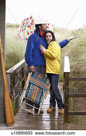 Stock Image - Young couple on beach with umbrella. Fotosearch