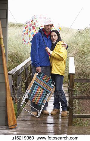 Young couple on beach with umbrella View Large Photo Image Stock Image - Young couple on beach with umbrella. Fotosearch