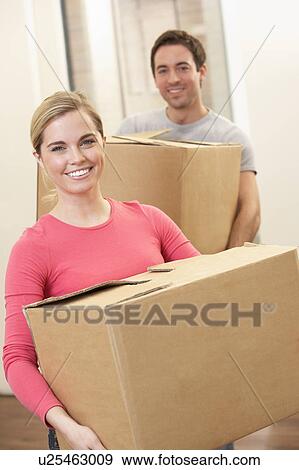 Stock Photo - Young couple on moving day carrying cardboard boxes. Fotosearch