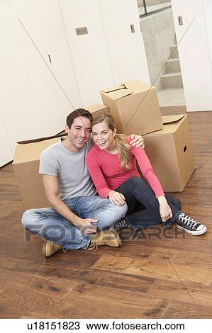 Stock Image - Young couple on moving day sitting with cardboard boxes. Fotosearch