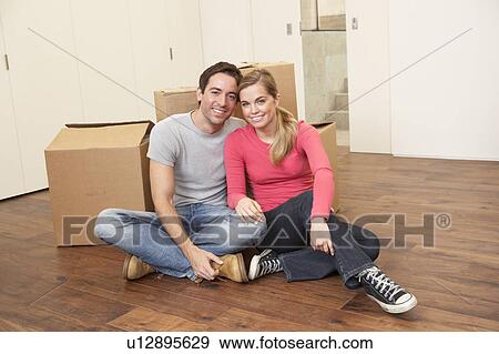 Stock Photo - Young couple on moving day sitting with cardboard boxes. Fotosearch