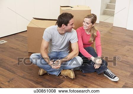 Stock Photo - Young couple on moving day sitting with cardboard boxes. Fotosearch