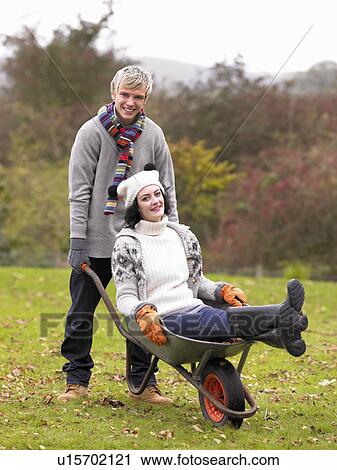 Young couple playing in wheelbarrow View Large Photo Image Stock Image - Young couple playing in wheelbarrow. Fotosearch
