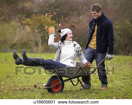 Young couple playing in wheelbarrow View Large Photo Image Stock Image - Young couple playing in wheelbarrow. Fotosearch