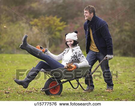 Stock Photograph - Young couple playing in wheelbarrow. Fotosearch