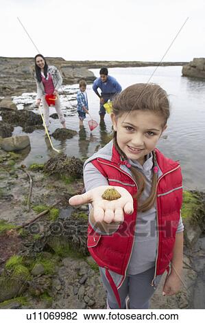 Stock Image - Young family at beach collecting shells. Fotosearch