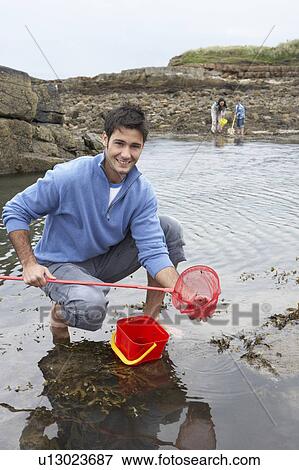 Stock Photo - Young family at beach collecting shells. Fotosearch