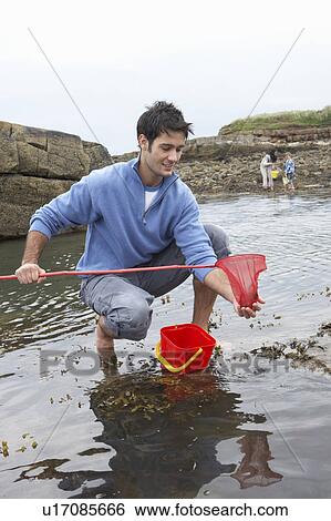 Stock Photograph - Young family at beach collecting shells. Fotosearch