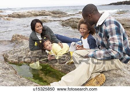 Stock Image - Young family with fishing net on rocks. Fotosearch