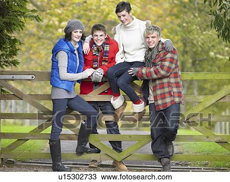 Young friends sitting on fence View Large Photo Image Stock Image - Young friends sitting on fence. Fotosearch