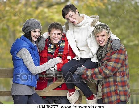 Young friends sitting on fence View Large Photo Image Stock Photo - Young friends sitting on fence. Fotosearch