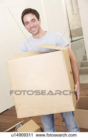 Young man on moving day holding and carrying cardboard box View Large Photo Image Stock Image - Young man on moving day holding and carrying cardboard box. Fotosearch