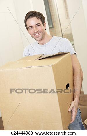 Young man on moving day holding and carrying cardboard box View Large Photo Image Stock Photo - Young man on moving day holding and carrying cardboard box. Fotosearch