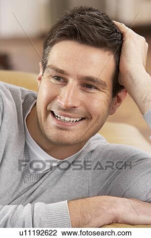 Stock Image - Young Man Relaxing In Chair At Home. Fotosearch