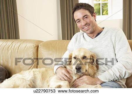 Young man with dog sitting on sofa View Large Photo Image Stock Image - Young man with dog sitting on sofa. Fotosearch