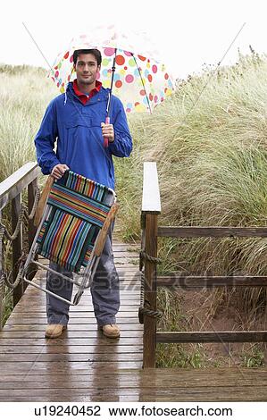 Stock Image - Young man with umbrella. Fotosearch