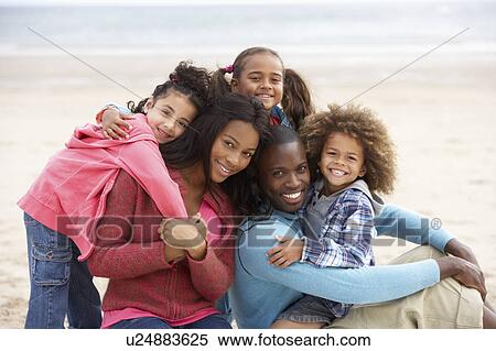 Stock Photography - Young mixed race family embracing on beach. Fotosearch