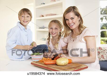 Young mother with children peeling vegetables in kitchen View Large Photo Image Picture - Young mother with children peeling vegetables in kitchen. Fotosearch