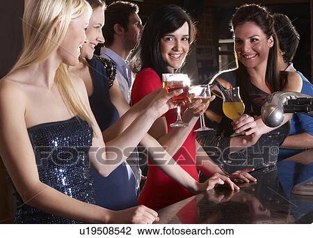 Stock Image - Young women drinking at bar. Fotosearch