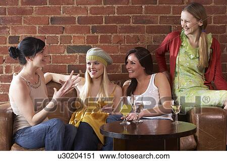 Stock Image - Young women sitting together and talking. Fotosearch