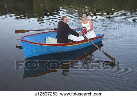 Stock Image - Bride and groom in row boat. Fotosearch