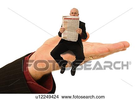 Picture - Businessman sitting on a huge hand reading the paper. Fotosearch